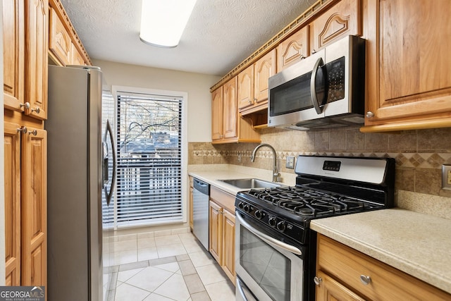 kitchen featuring sink, tasteful backsplash, a textured ceiling, light tile patterned flooring, and appliances with stainless steel finishes