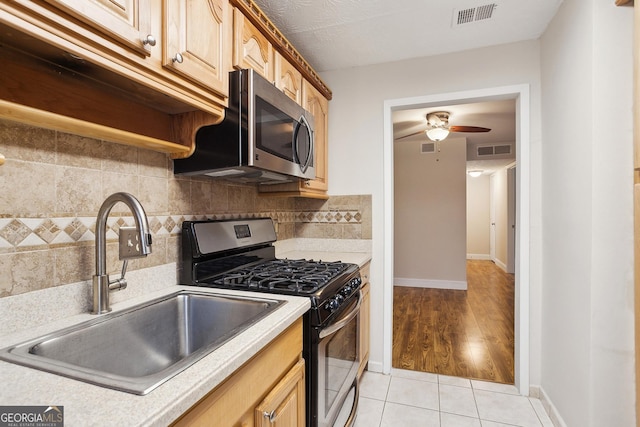 kitchen with light tile patterned flooring, decorative backsplash, stainless steel appliances, and sink