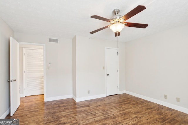 empty room featuring a textured ceiling, ceiling fan, and dark wood-type flooring