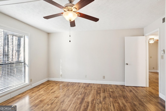 empty room with wood-type flooring, a textured ceiling, and ceiling fan