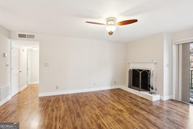 unfurnished living room featuring hardwood / wood-style flooring, ceiling fan, and a brick fireplace