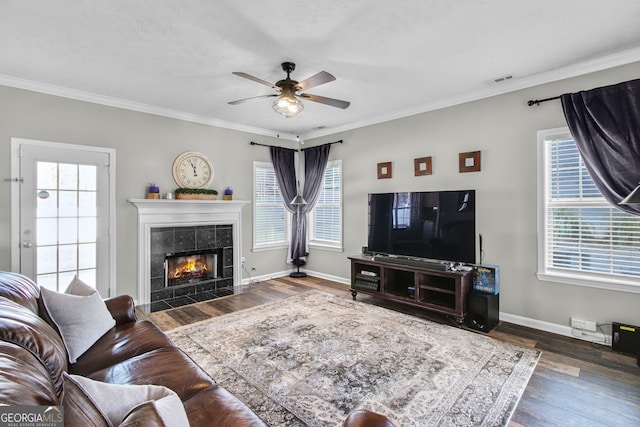 living room featuring ceiling fan, dark hardwood / wood-style floors, crown molding, a textured ceiling, and a fireplace