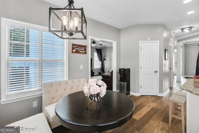 dining room with a healthy amount of sunlight, ceiling fan with notable chandelier, ornamental molding, and dark wood-type flooring