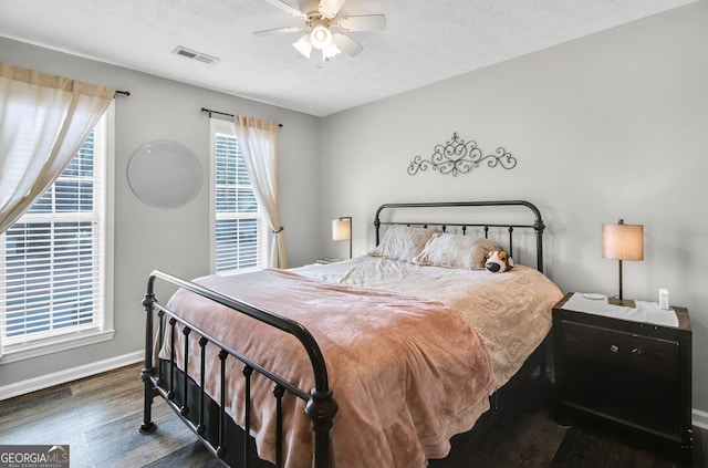 bedroom with a textured ceiling, dark hardwood / wood-style floors, and ceiling fan