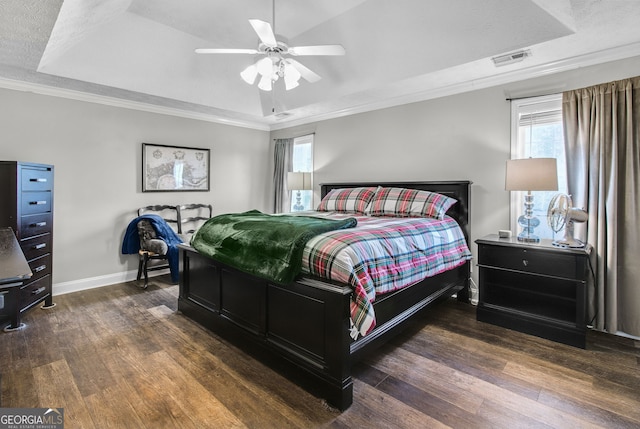 bedroom with a raised ceiling, ceiling fan, dark wood-type flooring, and ornamental molding