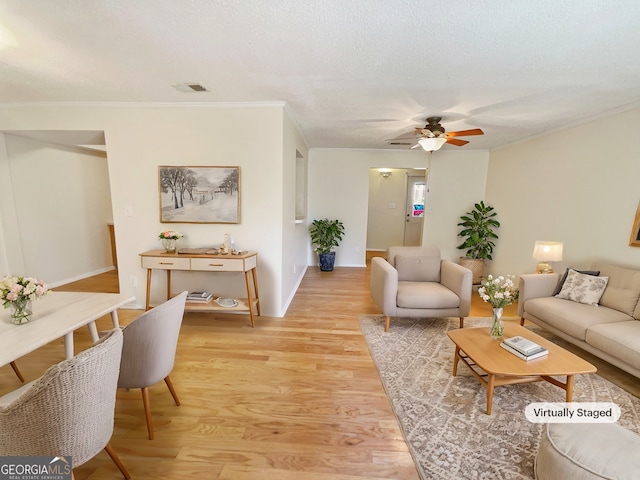 living room featuring light wood-type flooring, ceiling fan, and ornamental molding