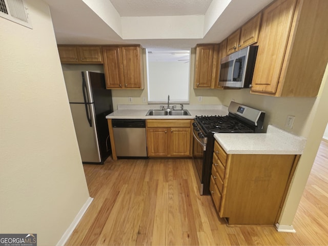 kitchen with sink, light hardwood / wood-style flooring, a textured ceiling, and appliances with stainless steel finishes