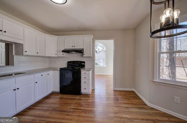 kitchen featuring black range with electric stovetop, dark wood-type flooring, light stone counters, backsplash, and white cabinets