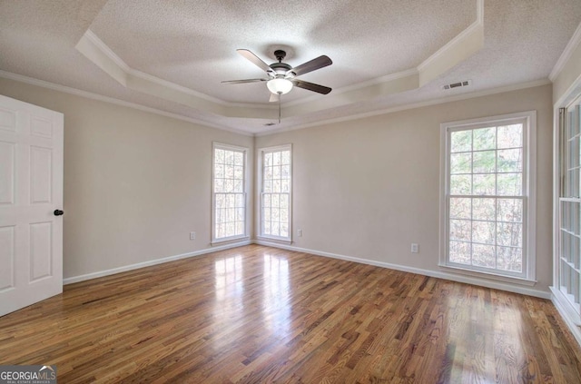 unfurnished room featuring a tray ceiling, crown molding, hardwood / wood-style floors, and a textured ceiling