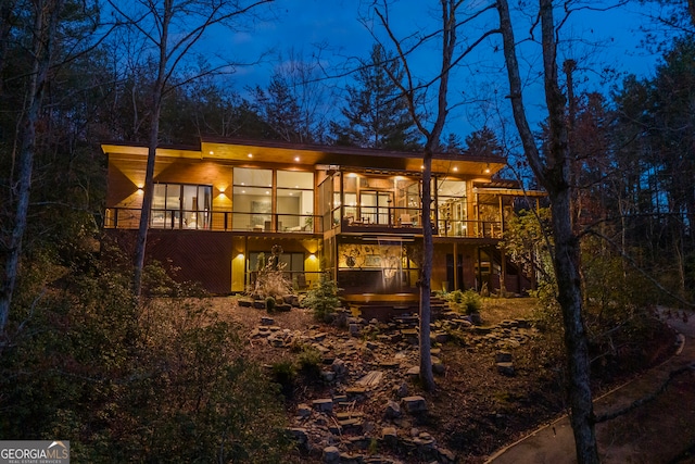 back house at night featuring a deck