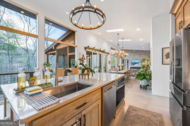 kitchen with sink, a center island, a chandelier, hanging light fixtures, and stainless steel appliances