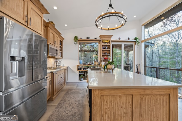 kitchen with a chandelier, appliances with stainless steel finishes, an island with sink, pendant lighting, and decorative backsplash