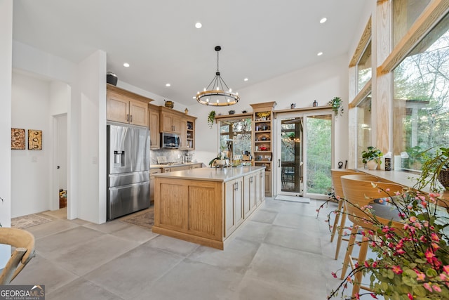 kitchen featuring hanging light fixtures, backsplash, stainless steel appliances, a kitchen island, and a chandelier