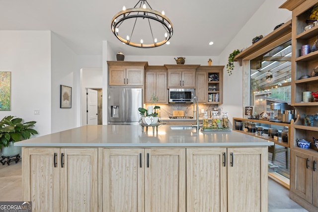 kitchen with an island with sink, appliances with stainless steel finishes, light brown cabinets, and an inviting chandelier