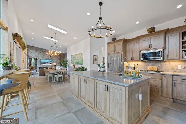 kitchen featuring a notable chandelier, hanging light fixtures, an island with sink, and appliances with stainless steel finishes