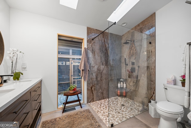 bathroom featuring vanity, a skylight, toilet, and tiled shower