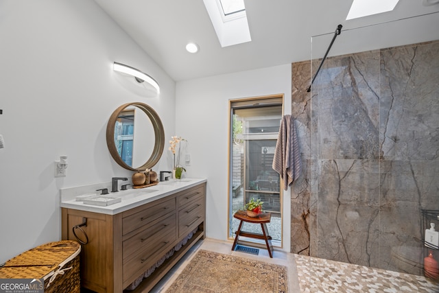 bathroom featuring vanity, vaulted ceiling with skylight, and tiled shower