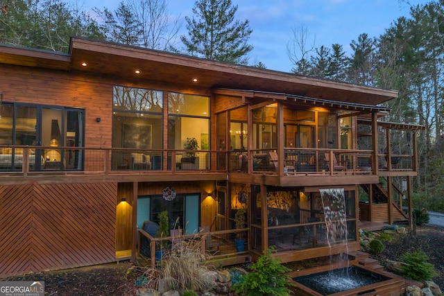 back house at dusk featuring a sunroom