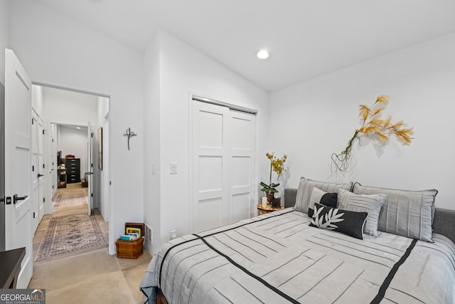 bedroom with lofted ceiling, light colored carpet, and a closet