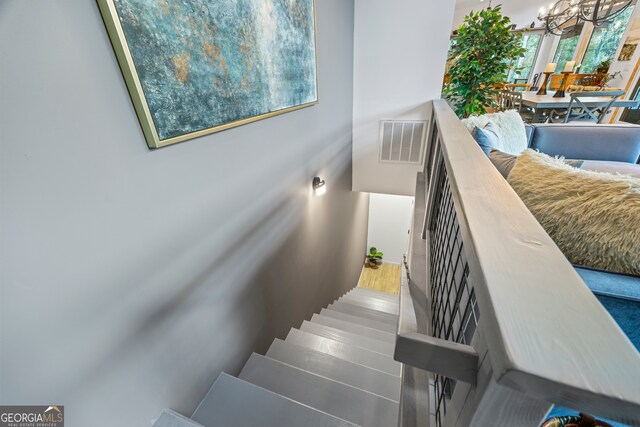 stairs with an inviting chandelier and hardwood / wood-style flooring