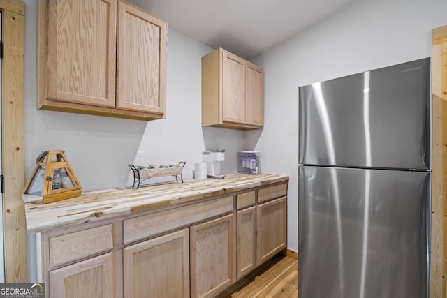 kitchen with wood counters, stainless steel fridge, light brown cabinetry, and light hardwood / wood-style flooring