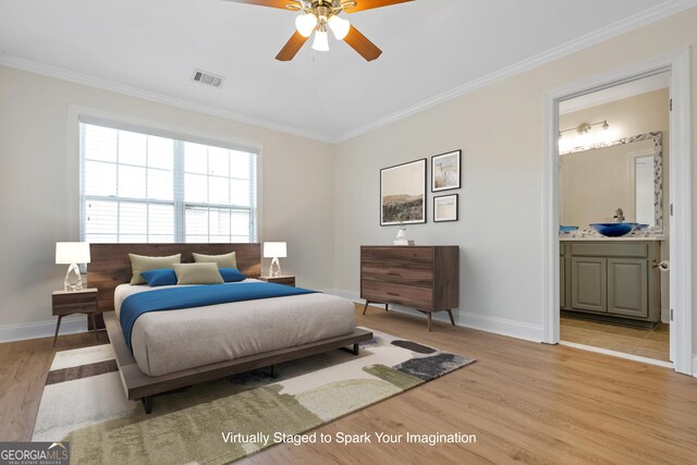 bedroom featuring ceiling fan, light hardwood / wood-style floors, ornamental molding, and connected bathroom