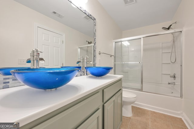 full bathroom with combined bath / shower with glass door, tile patterned floors, vanity, and toilet