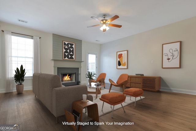 living room with dark hardwood / wood-style floors, a large fireplace, and ceiling fan