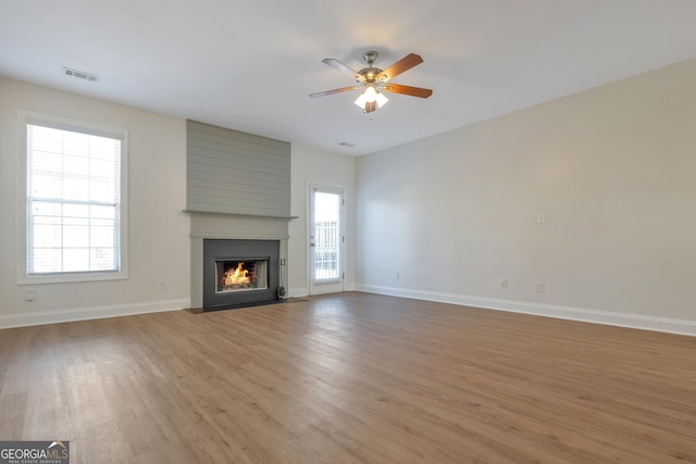 unfurnished living room with hardwood / wood-style flooring, ceiling fan, and a fireplace