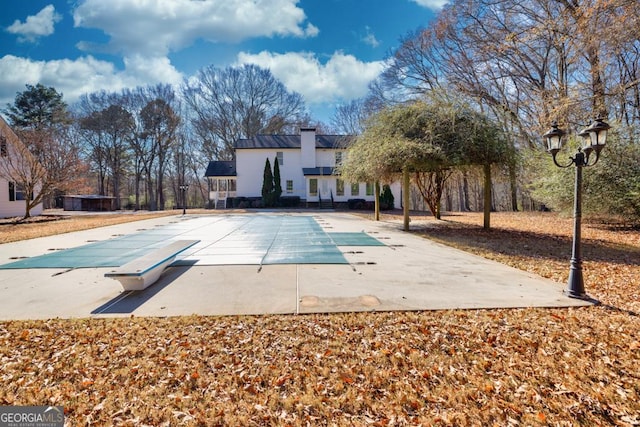 view of swimming pool with a diving board and a patio