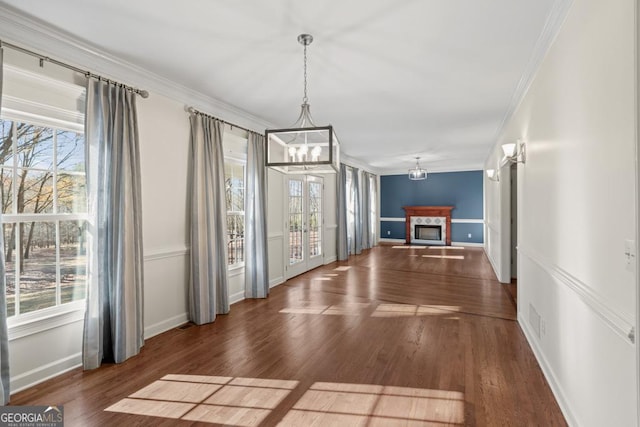 corridor with a healthy amount of sunlight, ornamental molding, dark wood-type flooring, and an inviting chandelier