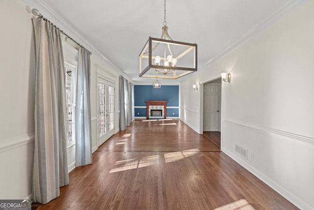 unfurnished dining area featuring a chandelier, dark hardwood / wood-style floors, and crown molding