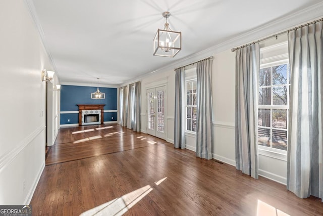 unfurnished living room featuring a healthy amount of sunlight, dark hardwood / wood-style floors, and ornamental molding