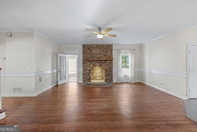 unfurnished living room featuring a stone fireplace, crown molding, ceiling fan, and dark hardwood / wood-style floors