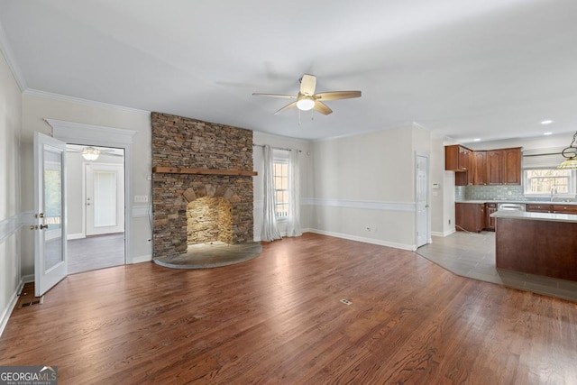 unfurnished living room with ceiling fan, plenty of natural light, wood-type flooring, and sink