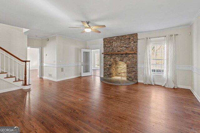 unfurnished living room with a fireplace, wood-type flooring, ceiling fan, and ornamental molding