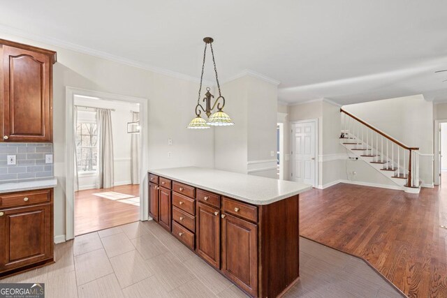 kitchen featuring backsplash, kitchen peninsula, crown molding, decorative light fixtures, and light tile patterned floors