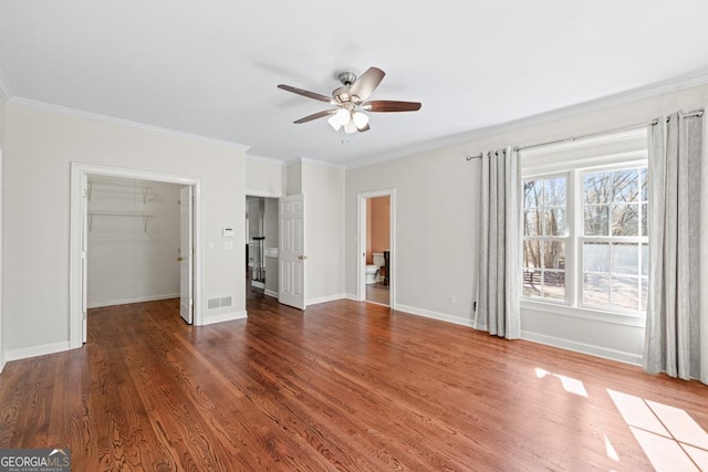 unfurnished bedroom with a spacious closet, a closet, ceiling fan, and ornamental molding