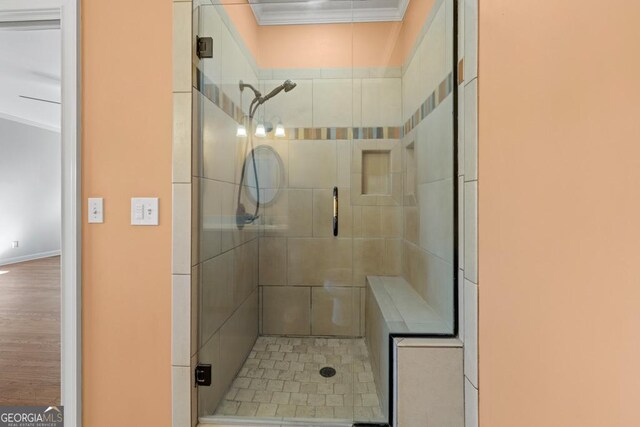 bathroom with crown molding and a shower with door