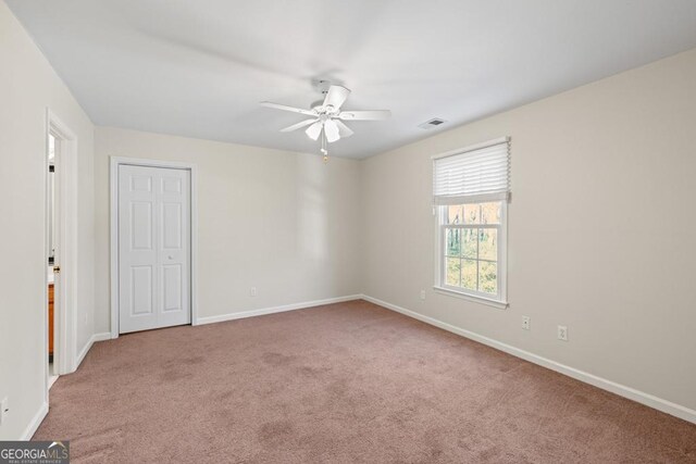 unfurnished room with ceiling fan and carpet