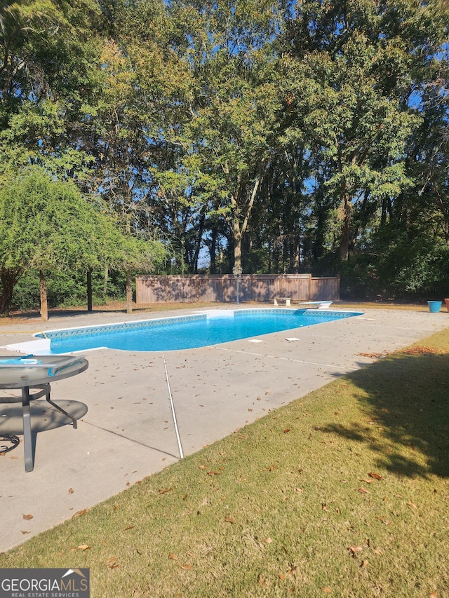 view of pool featuring a lawn, a patio area, and a diving board