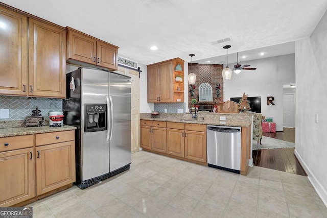 kitchen featuring pendant lighting, sink, ceiling fan, light stone countertops, and appliances with stainless steel finishes