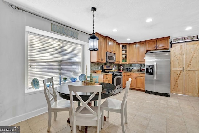 kitchen featuring decorative backsplash, appliances with stainless steel finishes, and pendant lighting