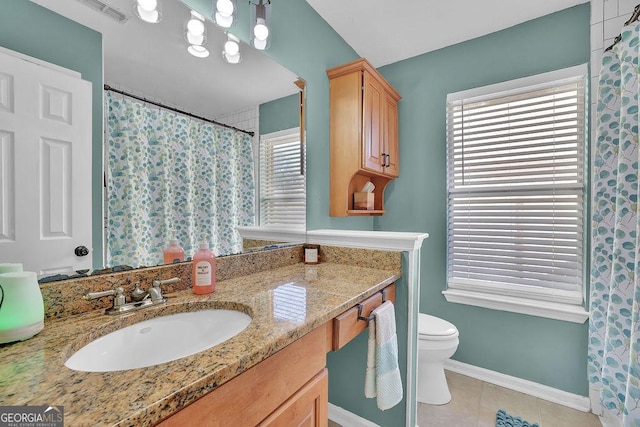 bathroom featuring tile patterned flooring, vanity, toilet, and a wealth of natural light