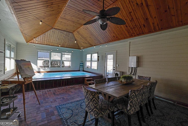 dining area featuring ceiling fan, wooden ceiling, and wood walls