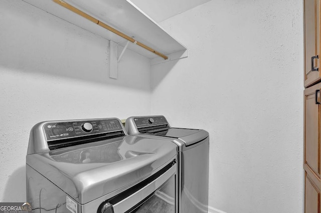 laundry area with washer and clothes dryer and cabinets