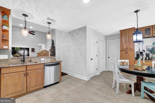 kitchen with sink, stainless steel dishwasher, ceiling fan, a textured ceiling, and light stone counters