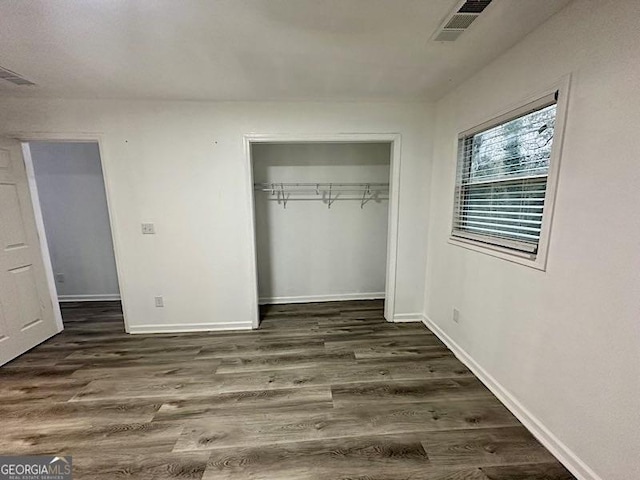 unfurnished bedroom featuring dark hardwood / wood-style floors and a closet