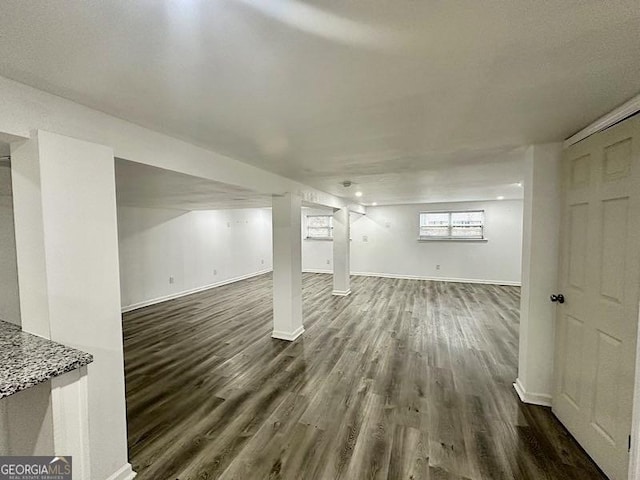 below grade area with dark wood-style flooring and baseboards