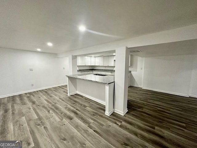 kitchen featuring baseboards, white cabinetry, dark wood finished floors, and light stone counters